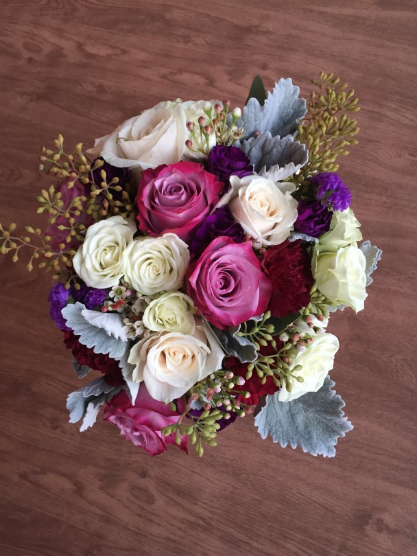 Alaska Winter Wedding | purple roses, plum mini carnations, burgundy carnations, white roses, dusty miller, eucalyptus and wax flower. Bound with white ribbon and a purple corset. Designed by Natasha Price of Alaskaknitnat.com