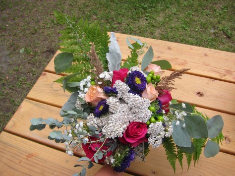 Alaska bridal bouquet with peach and fuchsia roses, purple Japanese aster, green hypericum berry, dusty miller, baby's breath, orange spray roses, seeded eucalyptus and foraged yarrow, grass and ferns. The perfect wild Alaska wedding bouquet. | Designed by Natasha Price of alaskaknitnat.com
