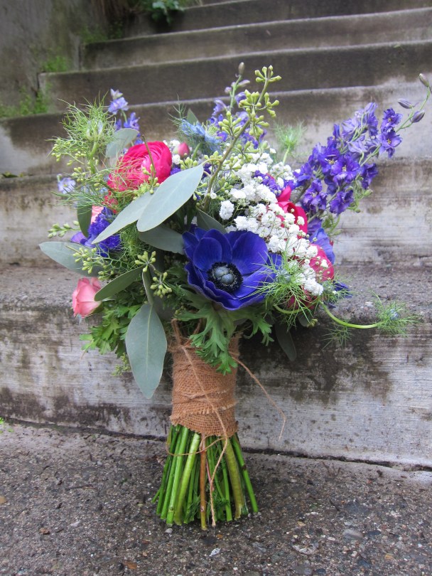 Bridal bouquet made with purple anemones, fuchsia ranunculus, blue nigella, purple larkspur, daisies, baby's breath, pink spray roses and seeded eucalyptus | designed by Natasha Price of Alaskaknitnat.com