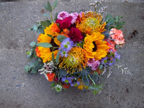 Alaska Weddings: a bridal bouquet made with sunflower, protea, mini carnation, button mums, mini asters, limonium and eucalyptus. Just perfect for a lakeside wedding. Designed by Natasha Price of Alaskaknitnat.com