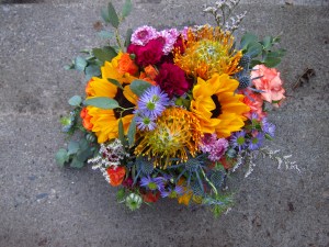 Alaska Weddings: a bridal bouquet made with sunflower, protea, mini carnation, button mums, mini asters, limonium and eucalyptus. Just perfect for a lakeside wedding. Designed by Natasha Price of Alaskaknitnat.com
