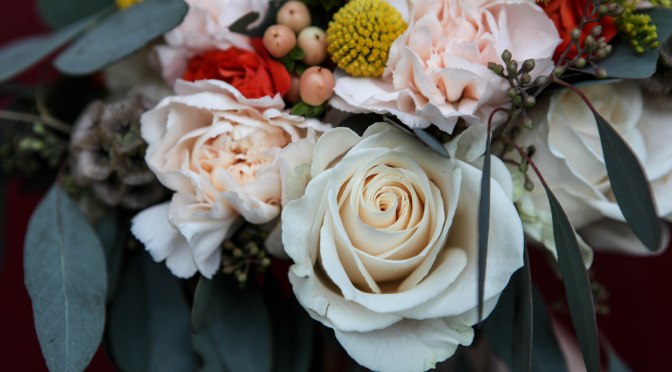 A perfect fall bridal bouquet. Solidago, white roses, orange spray roses, salmon hypericum berry, billy ball, scabiosa pods, peach carnation and seeded eucalyptus wrapped in burlap with jute twine corset | designed by Natasha Price of alaskaknitnat.com