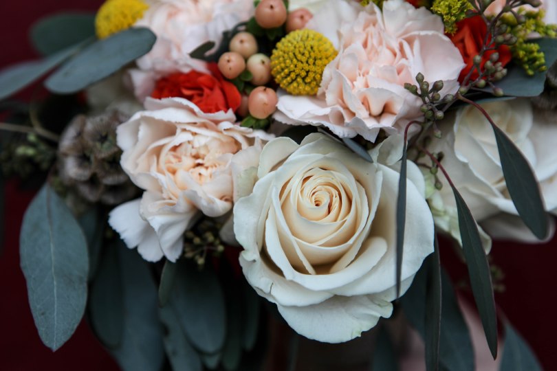 A perfect fall bridal bouquet. Solidago, white roses, orange spray roses, salmon hypericum berry, billy ball, scabiosa pods, peach carnation and seeded eucalyptus wrapped in burlap with jute twine corset | designed by Natasha Price of alaskaknitnat.com